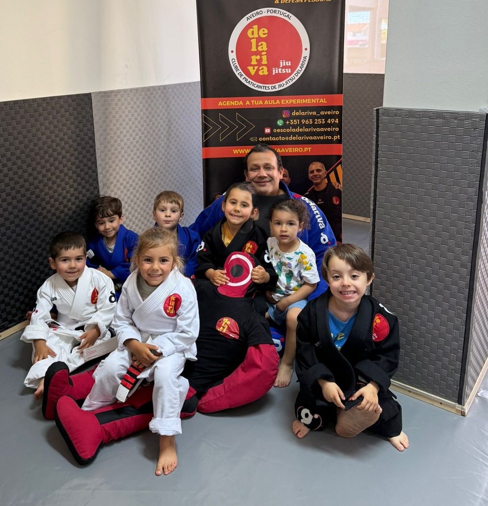 Turma Kids I com o professor, em frente ao cartaz da Escola Delariva Aveiro